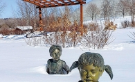 Boy and girl statues in Plymouth's Millennium Garden covered in snow.