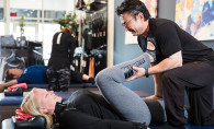 A Flexologist helps a woman with assisted stretching at StretchLab of Plymouth.