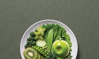 A plate full of healthy, green food options like kiwis, apples, peas, limes and more.