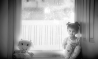 A girl sits six feet from her stuffed animal.