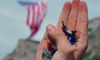 A hand holding the Eagle Scout badge makes the Boy Scouts' salute.