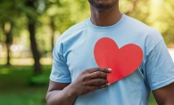 A volunteer holds a paper heart in front of his chest.