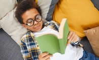 Boy reading book while laying down