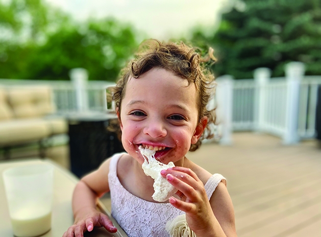 A young girl messily eating a s'more