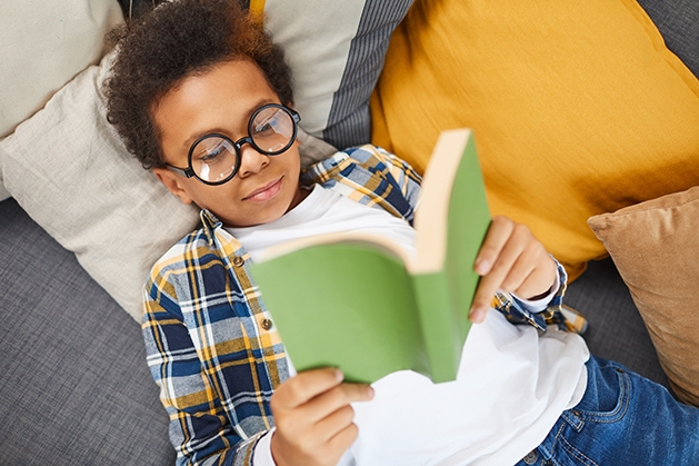 Boy reading book while laying down