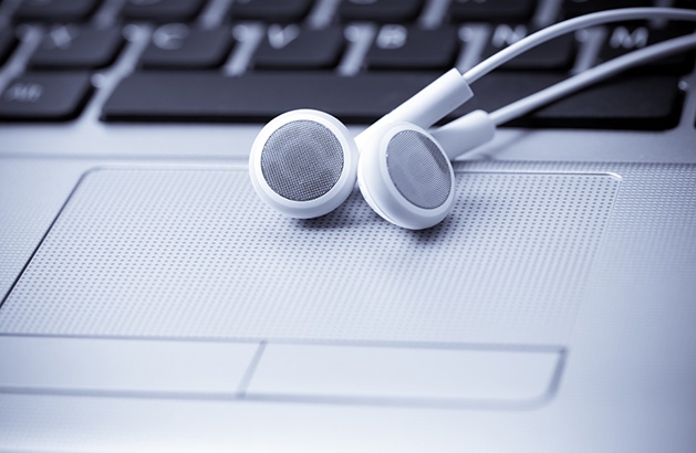 Podcast recommendation A pair of white headphones rest on a laptop.