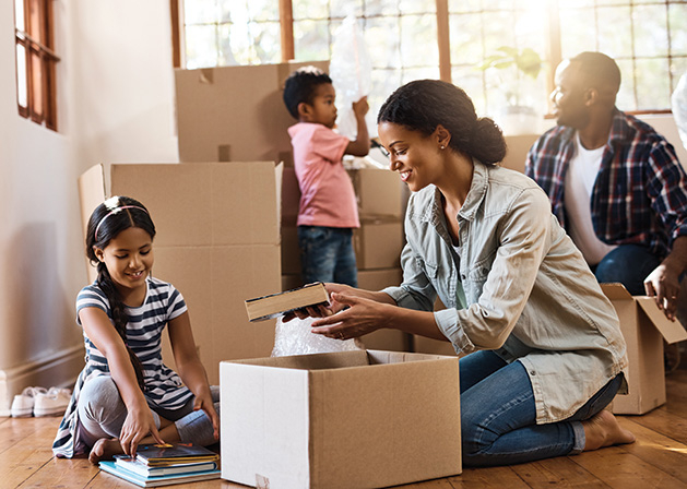 A family packs boxes, preparing for a move with kids.