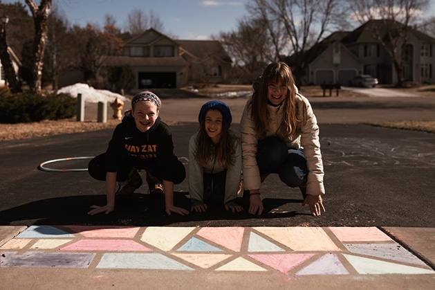 Ann Grocholski and her kids pose with their sidewalk chalk mural.