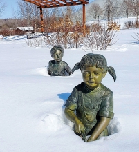 Boy and girl statues in Plymouth's Millennium Garden covered in snow.