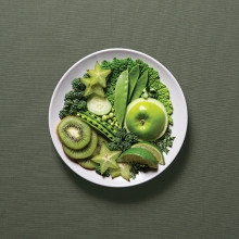 A plate full of healthy, green food options like kiwis, apples, peas, limes and more.