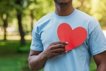 A volunteer holds a paper heart in front of his chest.