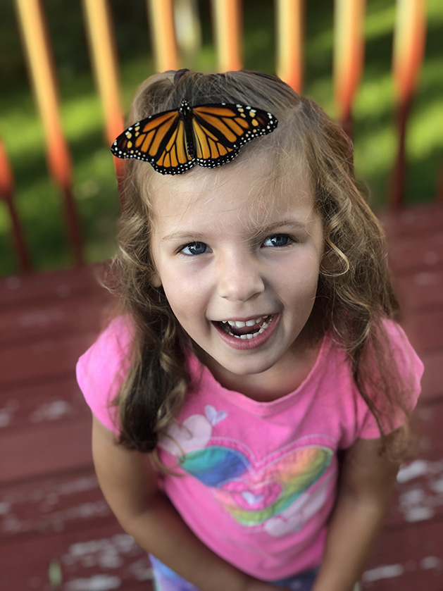 A monarch butterfly on a girl's head