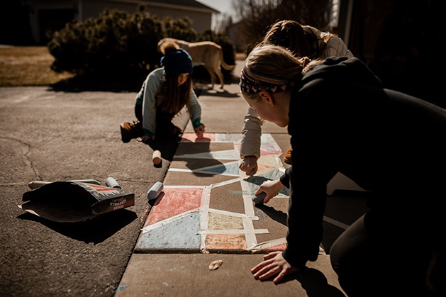 Ann Grocholski and her children work on a sidewalk chalk mural.